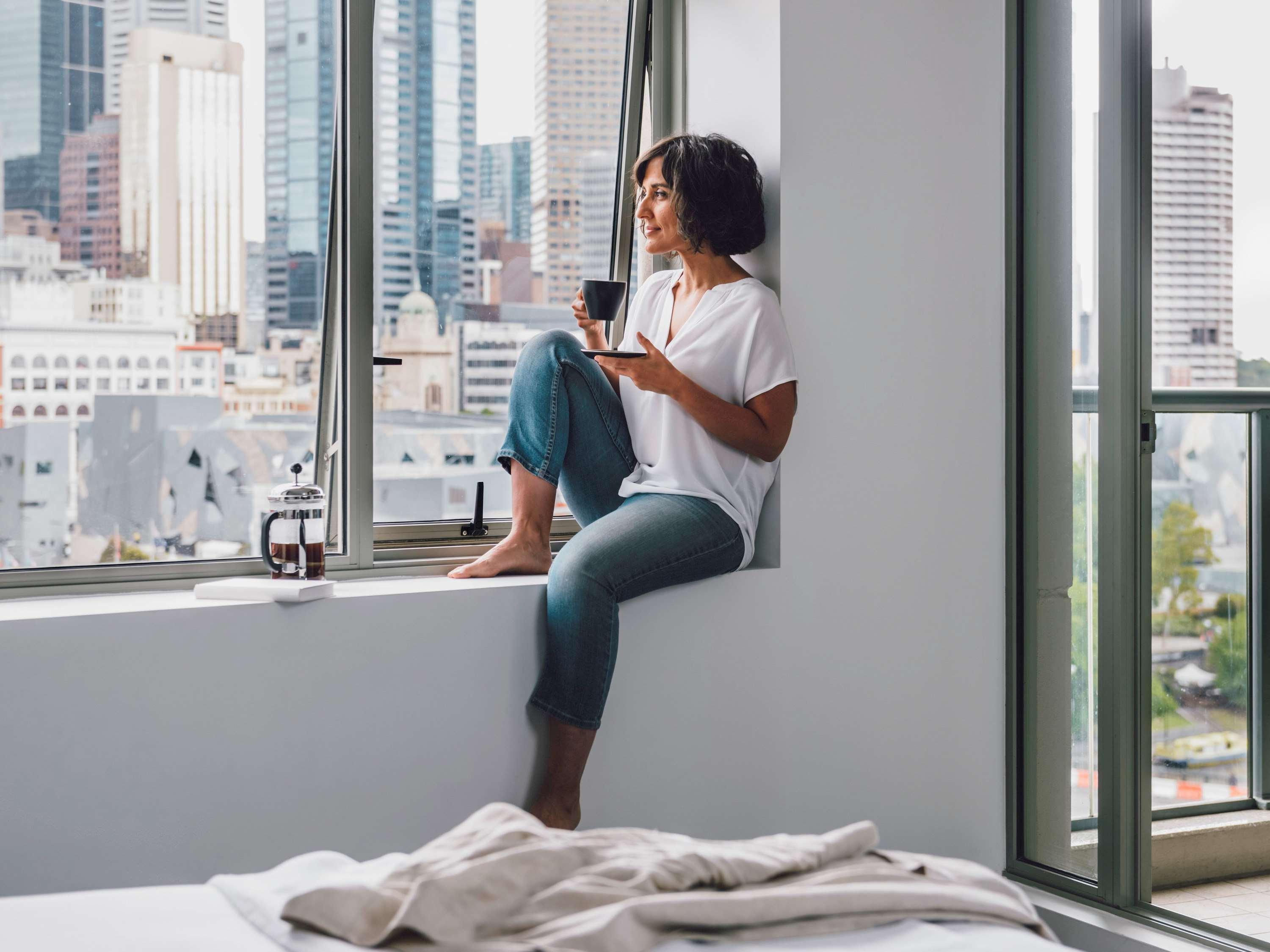 Quay West Suites Melbourne Zewnętrze zdjęcie A woman sitting on a windowsill